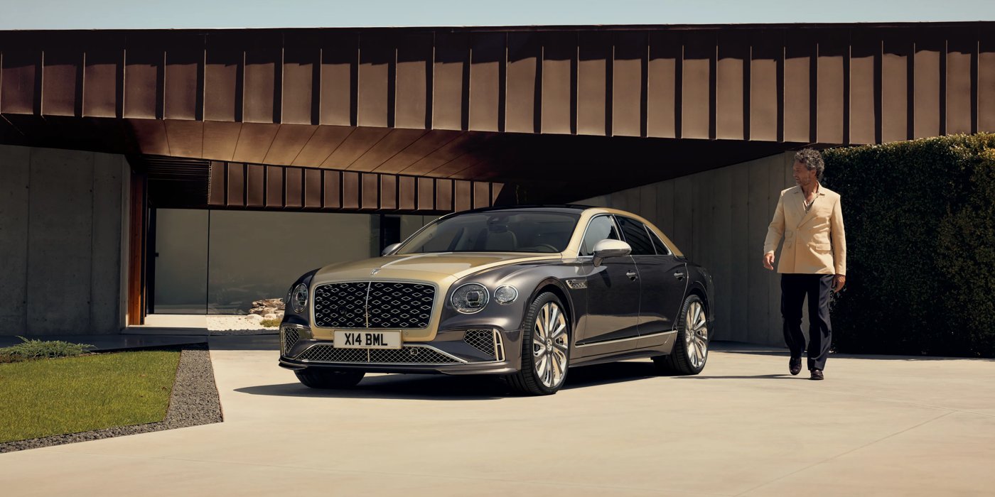 Bentley Kaohsiung Bentley New Flying Spur Mulliner V8 hybrid sedan front three quarters in Rose Gold over Magnetic paint, parked near modern home