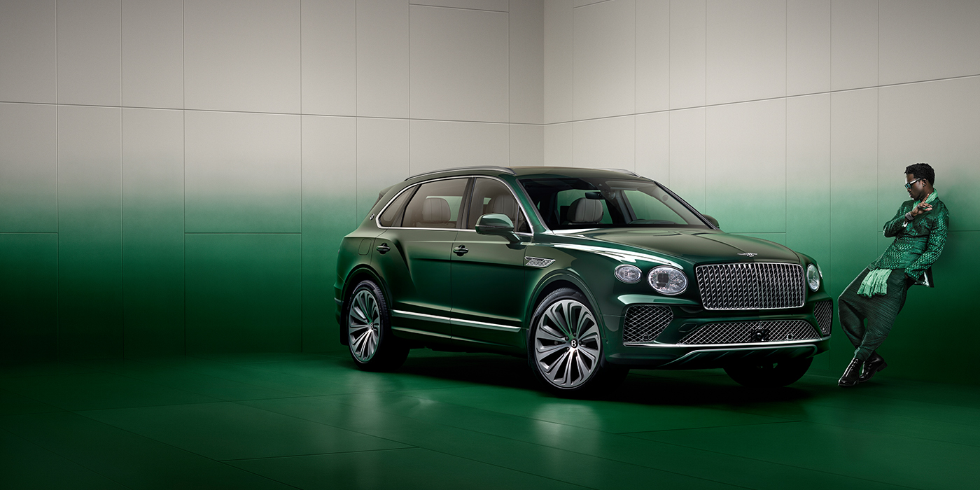 Bentley Kaohsiung Wisdom K leans against wall next to Bentley Bentayga Extended Wheelbase Atelier Edition SUV in Light Emerald green paint