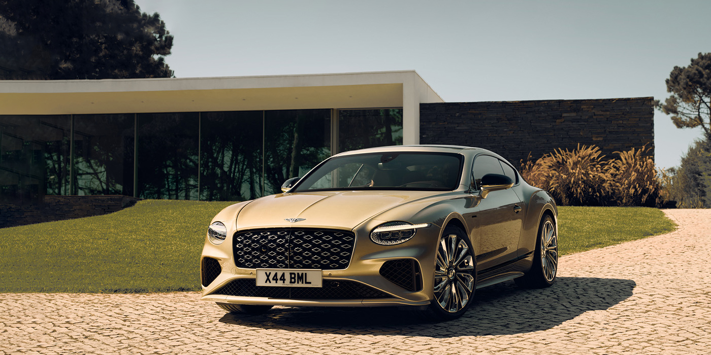Bentley Kaohsiung Bentley Continental GT Mulliner coupe front three quarters in Patina paint parked outside a glass fronted building with a grass lawn behind it