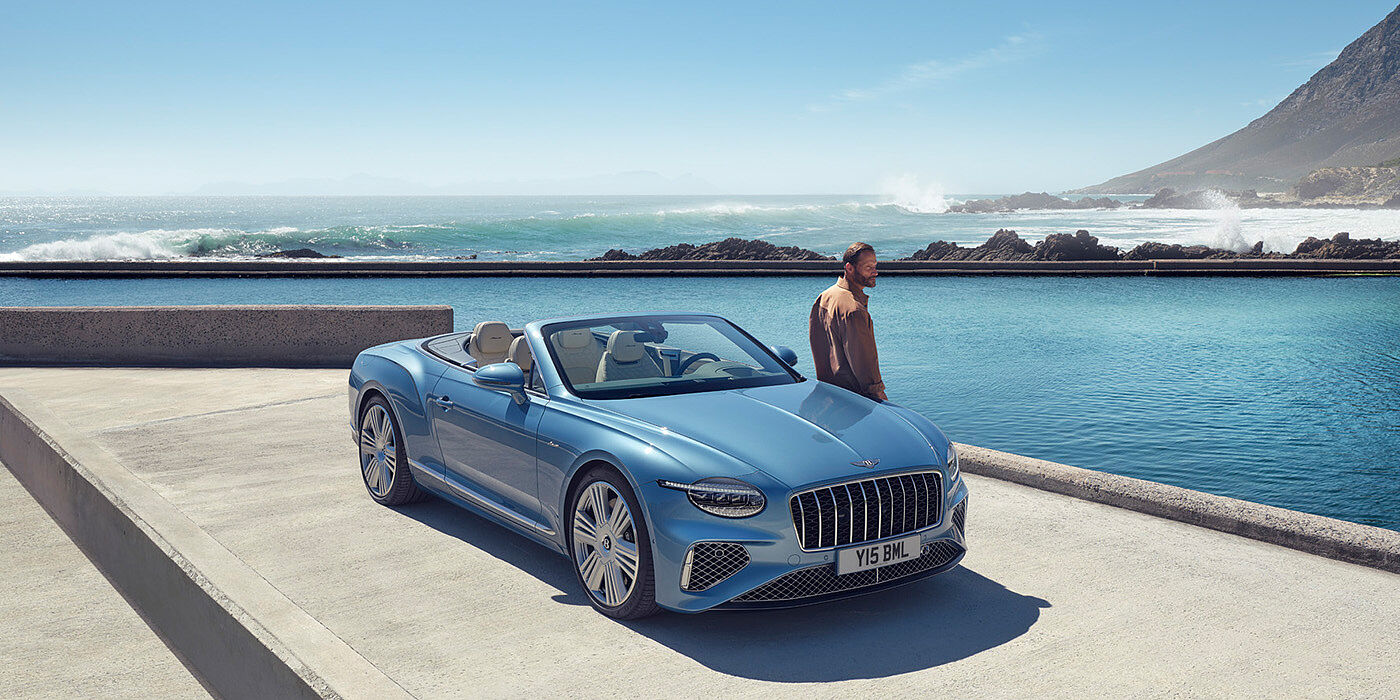 Bentley Kaohsiung New Bentley Continental GTC Azure convertible front view in Light Windsor blue paint with 22 inch ten spoke wheels parked by the sea in the sunshine