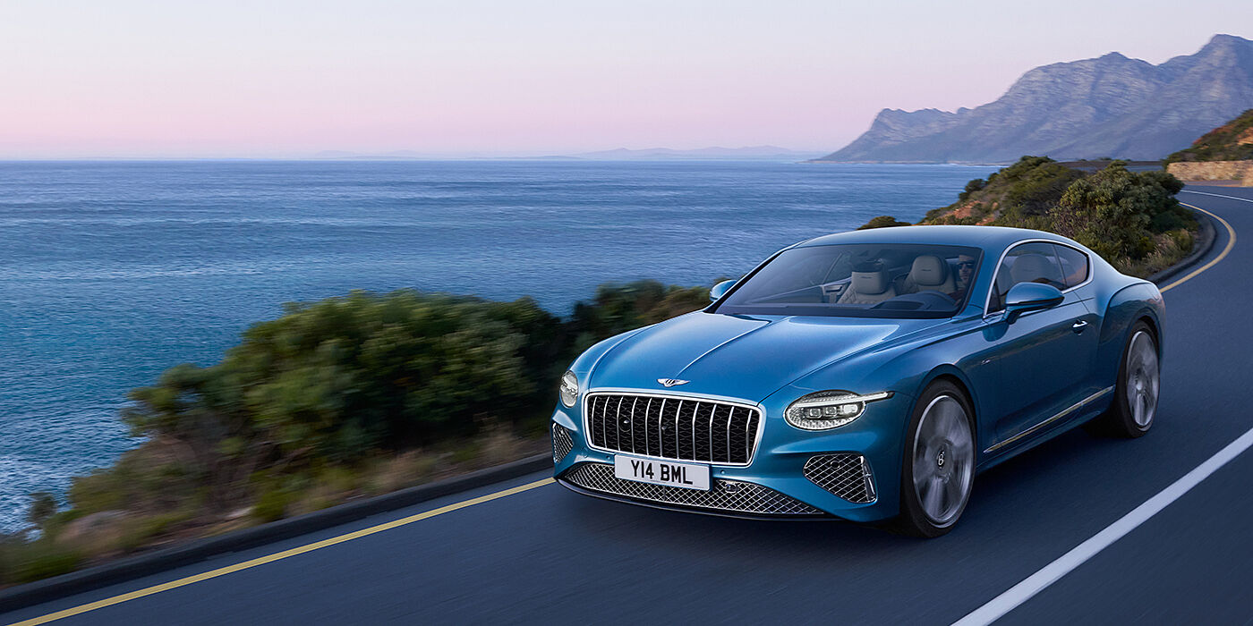 Bentley Kaohsiung New Bentley Continental GT Azure coupe in Light Windsor blue paint with 22 inch Azure wheels and chrome grill, driving dynamically by the sea