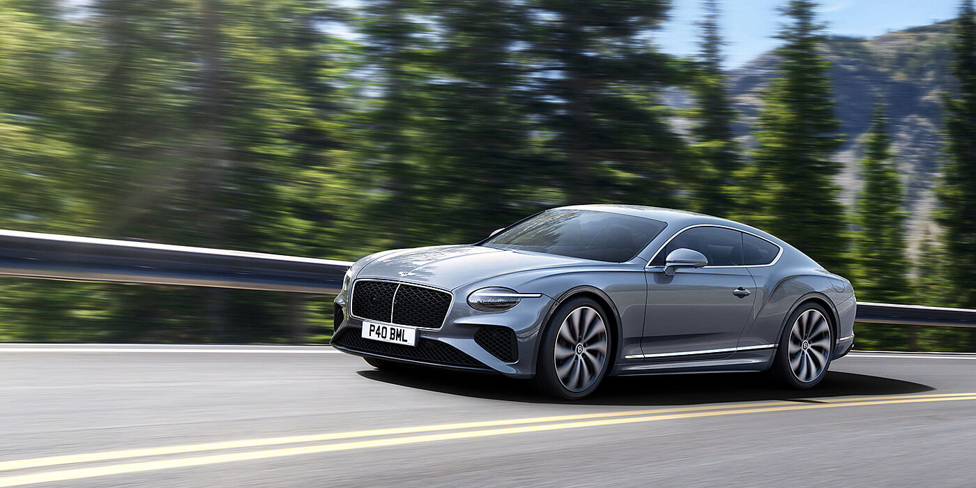 Bentley Kaohsiung New Bentley Continental GT coupe in Silverlake paint and 22 inch ten-spoke wheels, driving dynamically on a tree-lined road in the sunshine