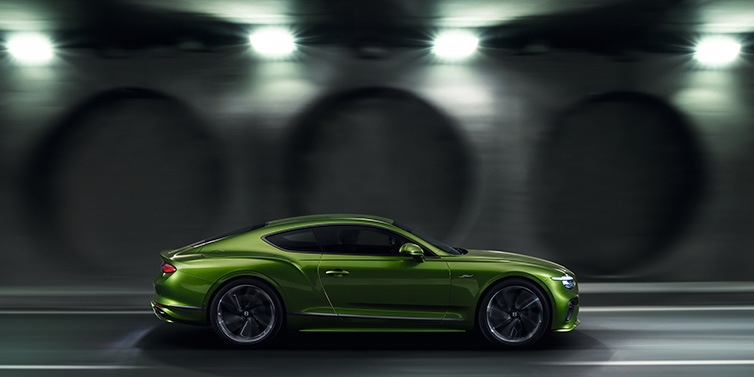 Bentley Kaohsiung Bentley Continental GT Speed coupe profile in Tourmaline Green drivig dynamically past a concrete wall at night